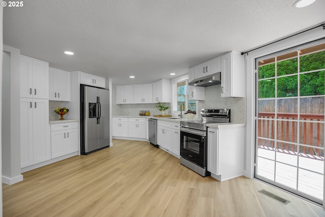 1111 SW Linneman Ave, Gresham, OR 97080 - kitchen featuring stainless steel appliances, light countertops, light wood-type flooring, decorative backsplash, and white cabinets