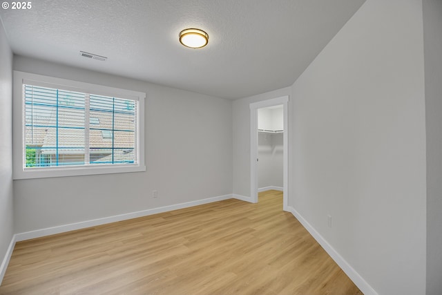 1111 SW Linneman Ave, Gresham, OR 97080 - unfurnished bedroom featuring light wood finished floors, a textured ceiling, a walk in closet, and a closet