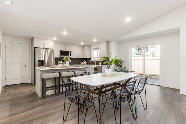 dining space with hardwood / wood-style flooring, lofted ceiling, and sink