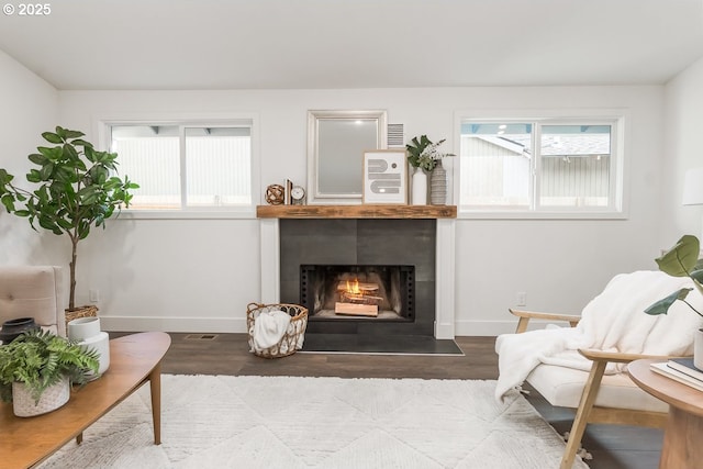 living area featuring a tile fireplace, plenty of natural light, and hardwood / wood-style flooring