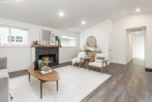 living room featuring a tiled fireplace, dark wood-type flooring, and vaulted ceiling