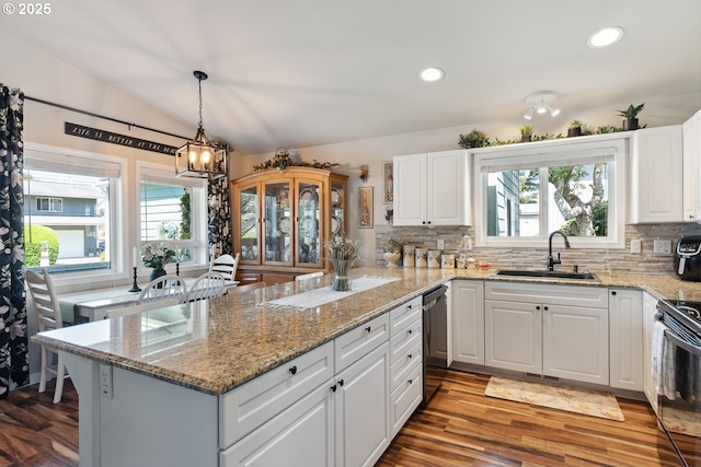 kitchen featuring a sink, dishwashing machine, plenty of natural light, backsplash, and vaulted ceiling