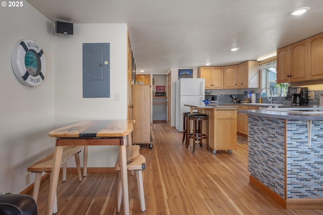 429 N Bridgeton Rd # 15, Portland, OR 97217 - kitchen featuring electric panel, light brown cabinets, light wood-style floors, a kitchen island, and freestanding refrigerator