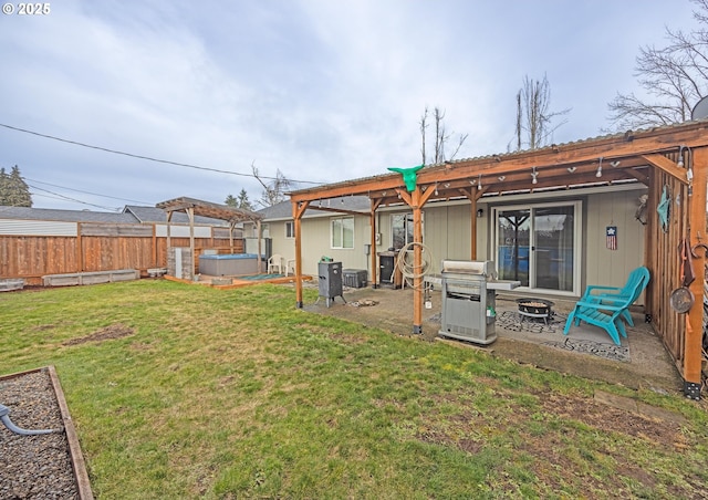 rear view of property featuring a hot tub, a lawn, a patio area, and an outdoor fire pit