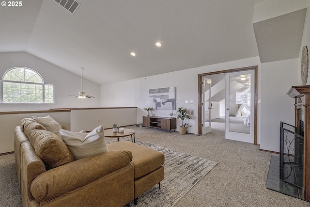 living area featuring light carpet, visible vents, a ceiling fan, lofted ceiling, and a fireplace