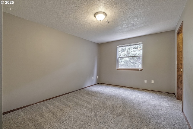 carpeted spare room featuring baseboards and a textured ceiling