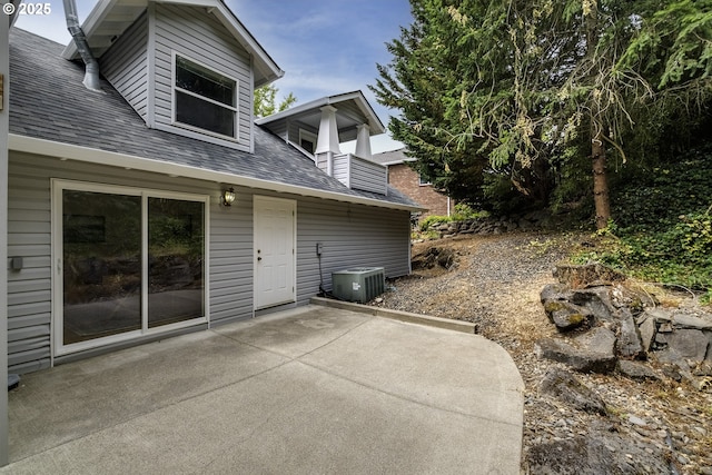 rear view of house with a shingled roof, central AC, and a patio