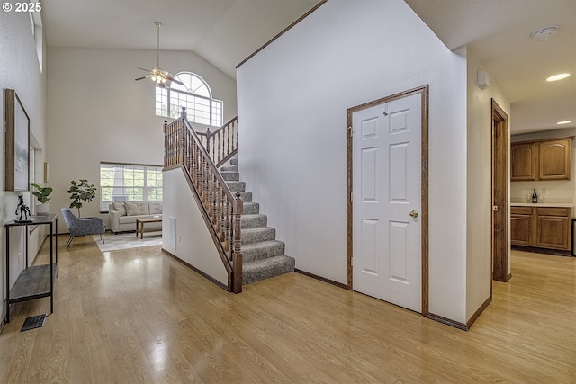 staircase with a ceiling fan, plenty of natural light, baseboards, and wood finished floors