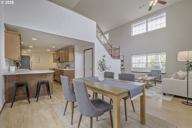 dining room featuring a ceiling fan, recessed lighting, light wood-style flooring, and stairs