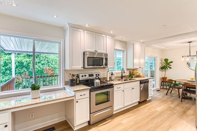 4080 SW 196th Ave, Beaverton, OR 97078 - kitchen with stainless steel appliances, white cabinets, light wood-type flooring, light stone counters, and a chandelier