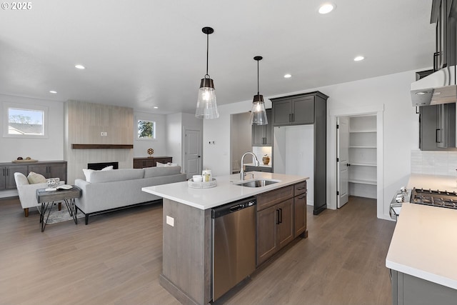 kitchen with pendant lighting, sink, hardwood / wood-style flooring, a kitchen island with sink, and stainless steel dishwasher