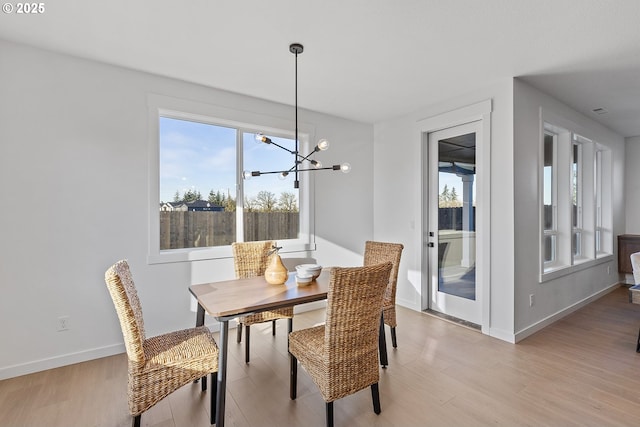 dining space featuring plenty of natural light, an inviting chandelier, and light wood-type flooring