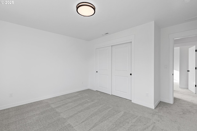 unfurnished bedroom featuring light carpet and a closet