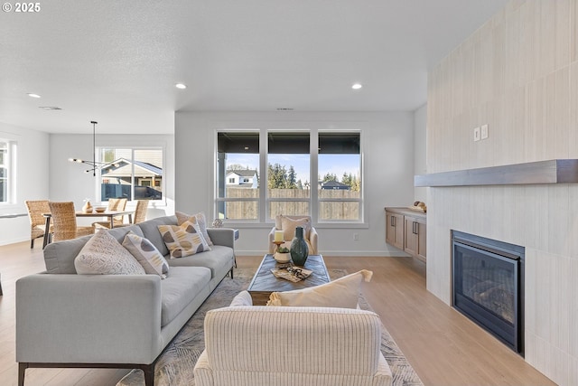 living room featuring a textured ceiling, a chandelier, and light hardwood / wood-style flooring