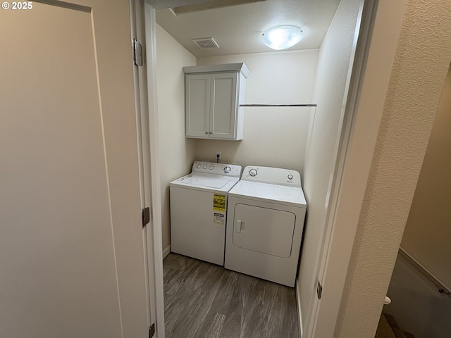 laundry area featuring cabinets, washing machine and dryer, a textured ceiling, and dark hardwood / wood-style flooring