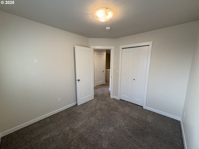 unfurnished bedroom with a closet, a textured ceiling, and dark colored carpet