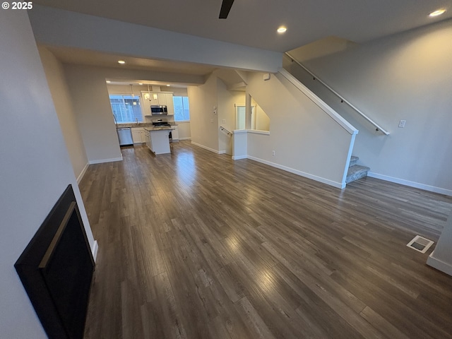 unfurnished living room featuring ceiling fan and dark wood-type flooring