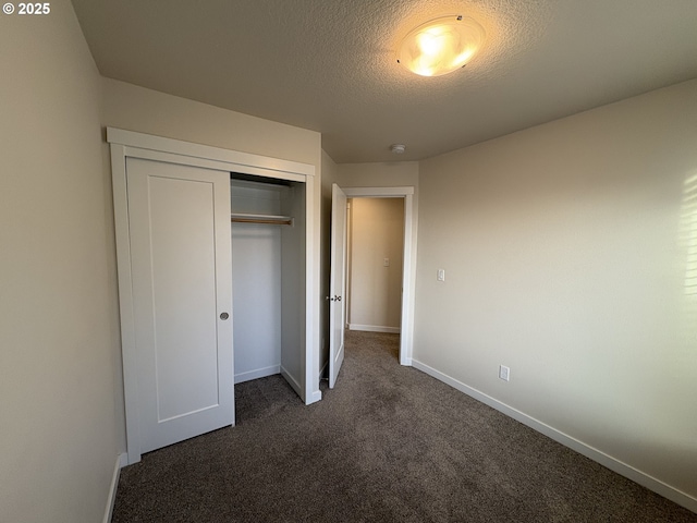 unfurnished bedroom with a closet, dark carpet, and a textured ceiling