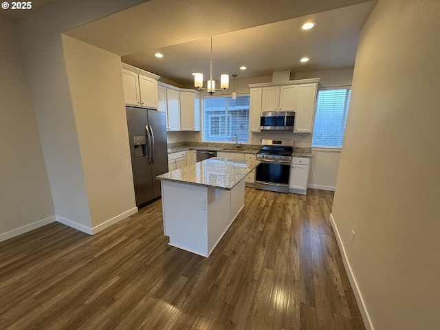 kitchen featuring appliances with stainless steel finishes, sink, pendant lighting, white cabinets, and a center island