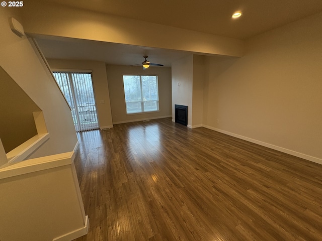 unfurnished living room with ceiling fan and dark wood-type flooring