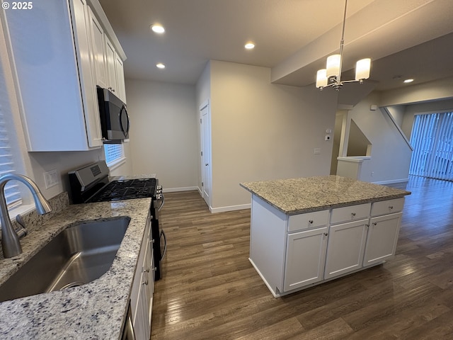 kitchen featuring pendant lighting, gas range, sink, and white cabinets