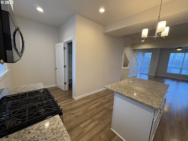 kitchen with pendant lighting, dark hardwood / wood-style floors, a center island, and light stone countertops