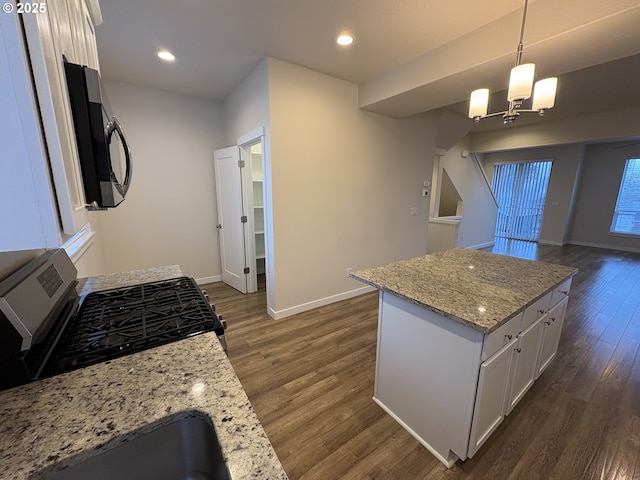 kitchen with stainless steel gas range oven, white cabinetry, dark hardwood / wood-style floors, a kitchen island, and pendant lighting