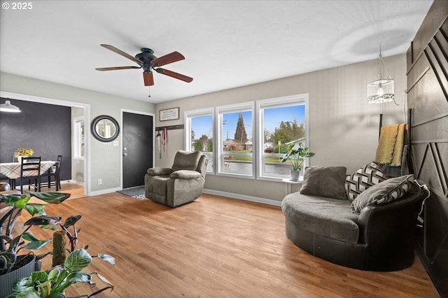 living room featuring a ceiling fan, wood finished floors, and baseboards