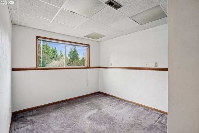 carpeted empty room with a paneled ceiling, baseboards, and visible vents