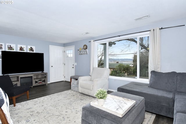 living room featuring a wealth of natural light, visible vents, and wood finished floors