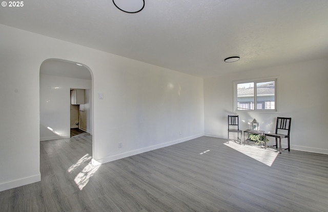 105 Redpath St, Kelso, WA 98626 - unfurnished living room featuring arched walkways, wood finished floors, and baseboards