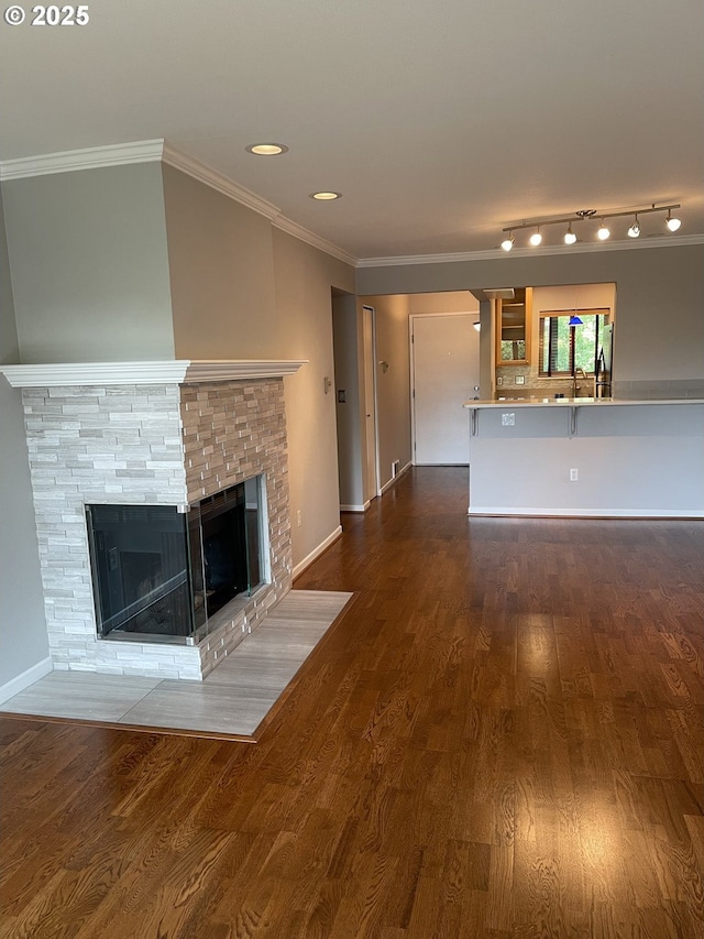 4970 S Landing Dr Unit 302, Portland, OR 97239 - unfurnished living room featuring crown molding, a multi sided fireplace, dark wood-style flooring, baseboards, and a sink
