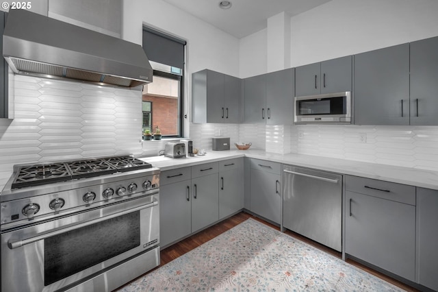 1634 NW Riverscape St, Portland, OR 97209 - kitchen featuring stainless steel appliances, wall chimney exhaust hood, gray cabinets, and tasteful backsplash