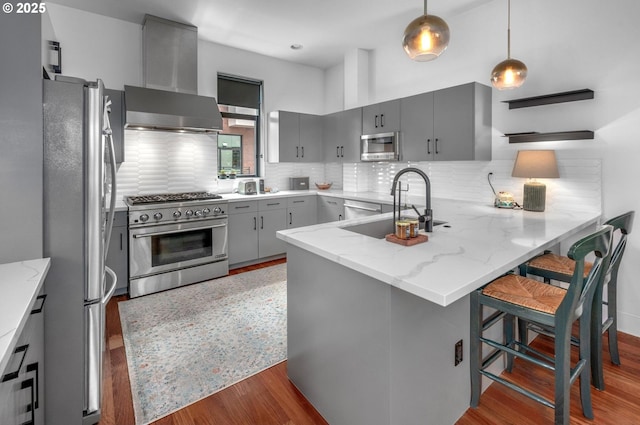 1634 NW Riverscape St, Portland, OR 97209 - kitchen featuring stainless steel appliances, gray cabinets, wall chimney range hood, and a peninsula