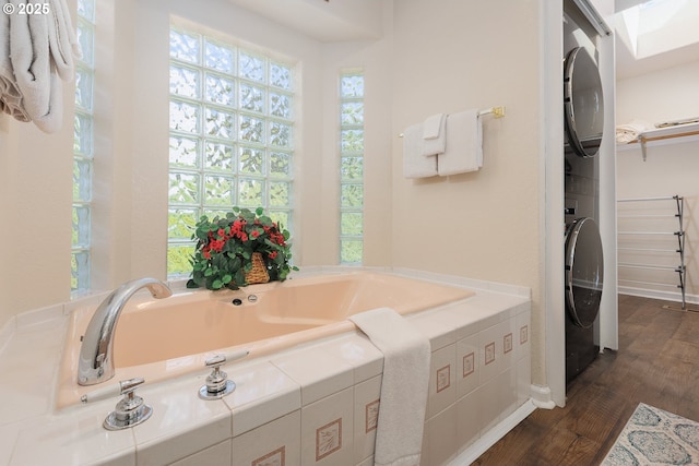461 Home Ct, Rockaway Beach, OR 97136 - bathroom featuring stacked washing machine and dryer, wood finished floors, a garden tub, and a spacious closet