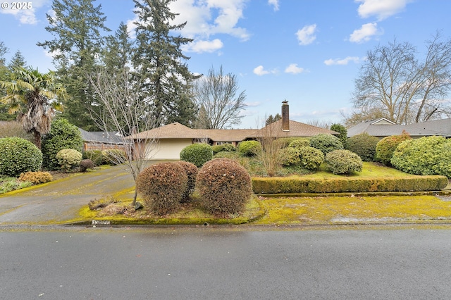 view of front of house featuring a garage, a chimney, and aphalt driveway