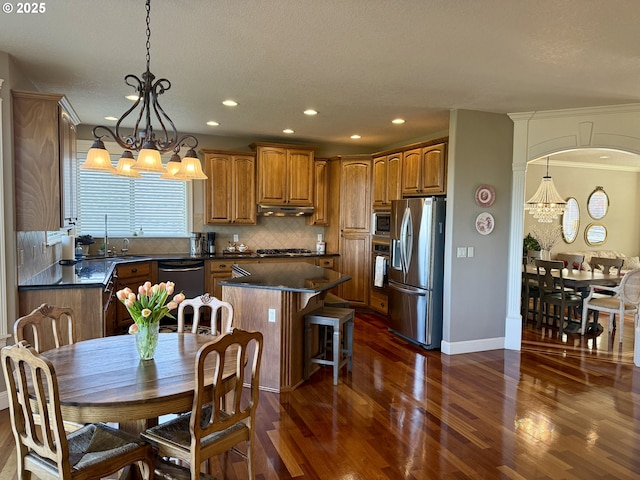 kitchen featuring appliances with stainless steel finishes, a chandelier, dark wood-type flooring, dark countertops, and recessed lighting