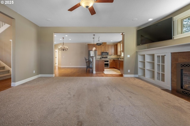 unfurnished living room with light colored carpet, a ceiling fan, baseboards, a tiled fireplace, and recessed lighting