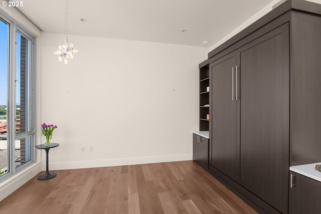 unfurnished dining area with plenty of natural light, light wood-style floors, and a chandelier