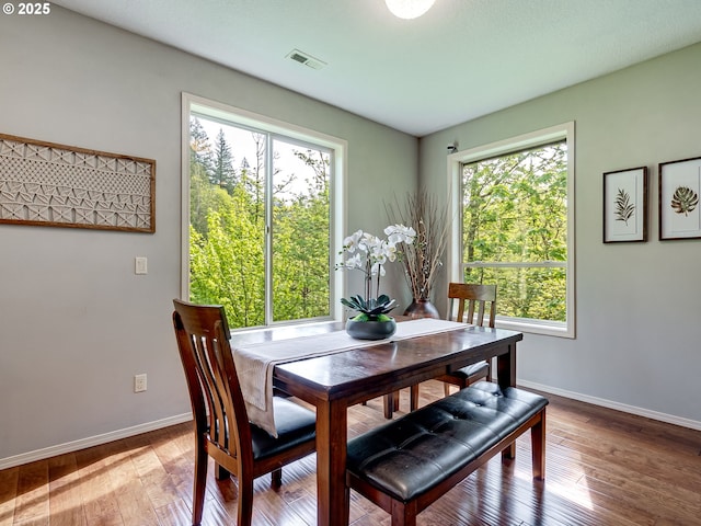 dining room featuring wood-type flooring, visible vents, and plenty of natural light