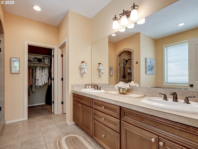 bathroom with a sink, a stall shower, a spacious closet, and tile patterned floors
