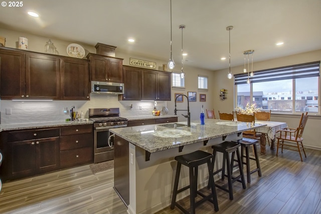 kitchen featuring a wealth of natural light, a sink, tasteful backsplash, appliances with stainless steel finishes, and light wood finished floors