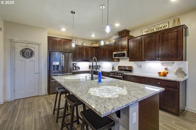 kitchen with light stone counters, appliances with stainless steel finishes, and wood finished floors