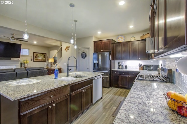 kitchen with a ceiling fan, light wood-style flooring, a sink, appliances with stainless steel finishes, and backsplash