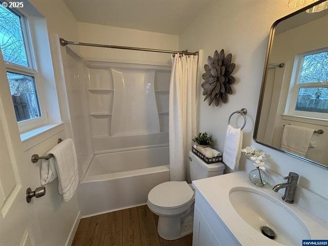 full bathroom featuring shower / bathtub combination with curtain, vanity, hardwood / wood-style flooring, and toilet