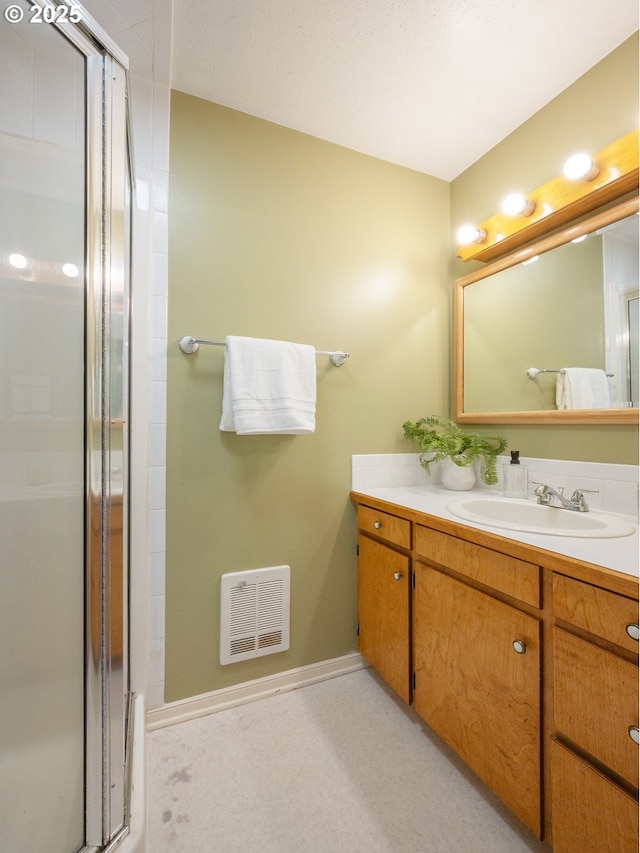 full bath featuring vanity, baseboards, a stall shower, and visible vents