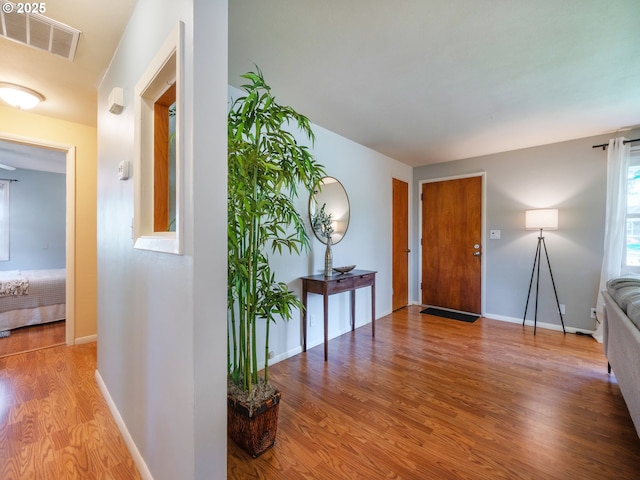 foyer featuring visible vents, baseboards, and wood finished floors