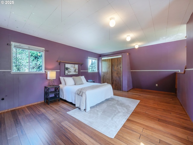 bedroom with baseboards, hardwood / wood-style floors, and multiple windows