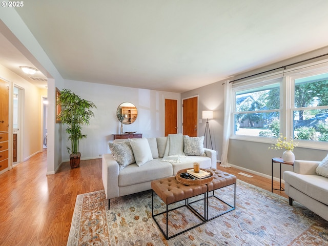 living area featuring baseboards, visible vents, and light wood-style floors