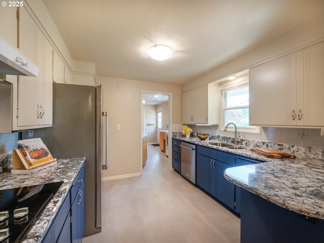 kitchen with baseboards, under cabinet range hood, a sink, blue cabinetry, and stainless steel appliances